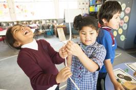 Primary students holding string and laughing.