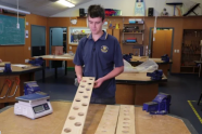 Student showing wood with holes cut in it for lightness