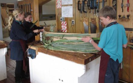 Students weaving flax onto the cardboard frame
