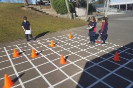 Students writing instructions to move through a grid painted outdoors