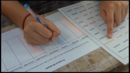 Student's hands filling in a worksheet and using the word mat