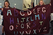 Students holding shade cloth with letters on it for a preschool