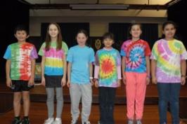 Six students showing their T-shirts at assembly