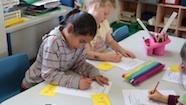 Primary students write at a table