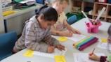 Years 1–2 students writing at their table