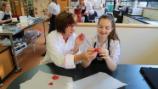 A technology teacher helping a student with shaping her cake decoration